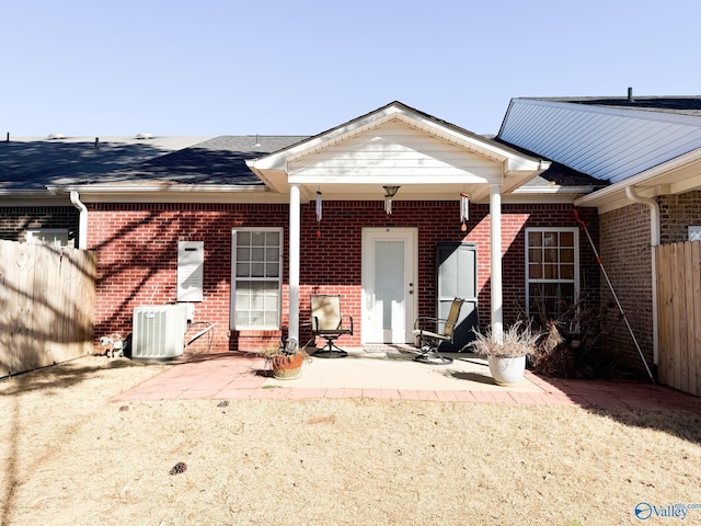 rear view of house with central AC, brick siding, a patio, and fence