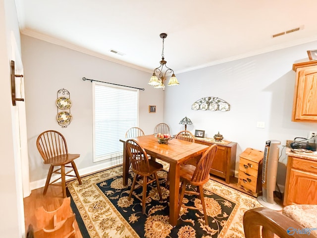 dining room featuring baseboards, light wood-style flooring, visible vents, and crown molding