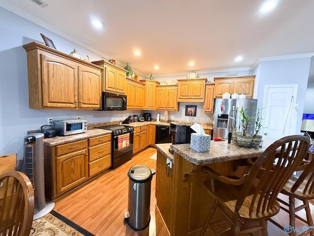 kitchen featuring a kitchen bar, recessed lighting, light wood-style floors, ornamental molding, and black appliances