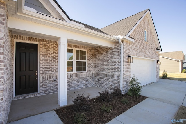 139 Jude Ln, Hazel Green, AL 35750 - property entrance featuring brick siding, a porch, concrete driveway, roof with shingles, and a garage