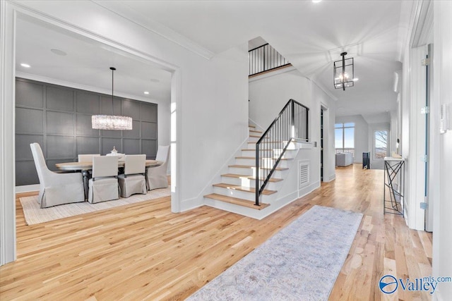 foyer featuring ornamental molding, a notable chandelier, stairway, and wood finished floors