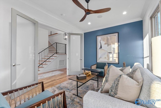 living room with visible vents, stairs, ornamental molding, and wood finished floors