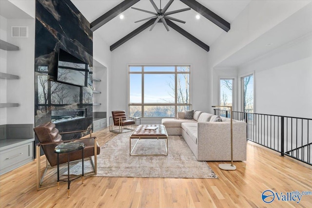 living area with built in shelves, beam ceiling, visible vents, wood finished floors, and high vaulted ceiling