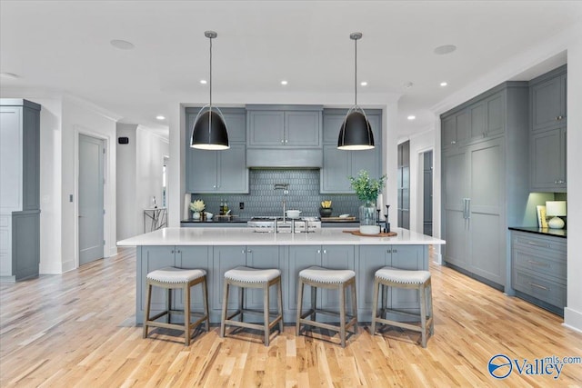 kitchen featuring light countertops, tasteful backsplash, light wood-style flooring, and a kitchen breakfast bar