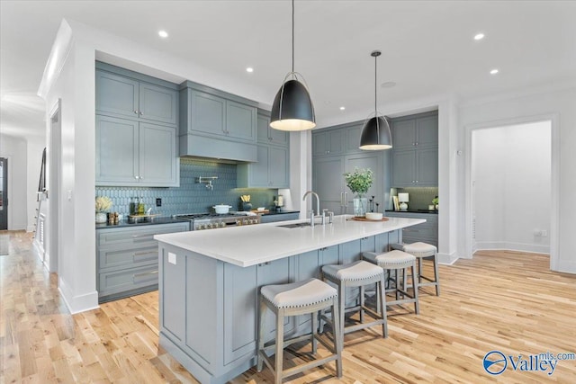 kitchen featuring light wood finished floors, backsplash, a sink, and stainless steel gas stovetop