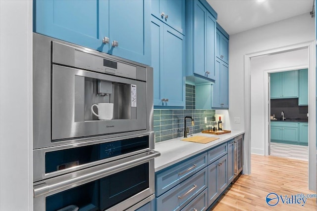 kitchen with blue cabinets, light wood finished floors, and oven