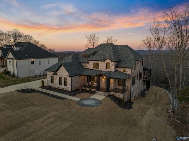 french country inspired facade with stone siding and curved driveway