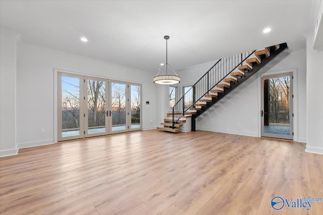 unfurnished living room with light wood-style floors, stairs, and baseboards