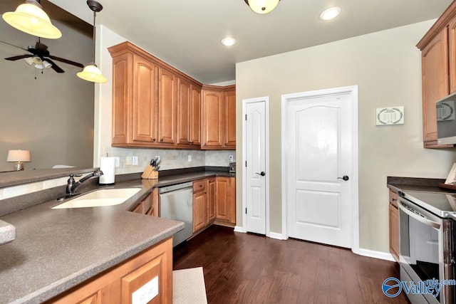 kitchen with dark countertops, appliances with stainless steel finishes, dark wood-type flooring, pendant lighting, and a sink