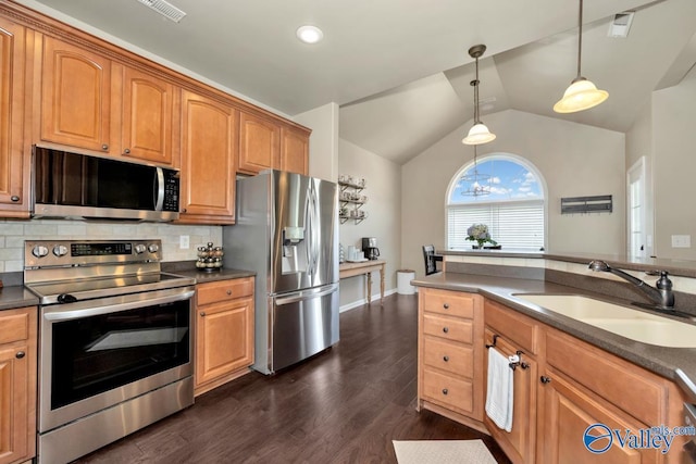 kitchen with lofted ceiling, a sink, appliances with stainless steel finishes, backsplash, and dark countertops