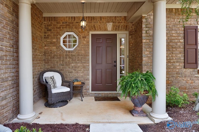 view of exterior entry with a porch and brick siding