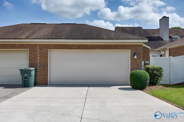 view of home's exterior featuring a garage, a shingled roof, and fence