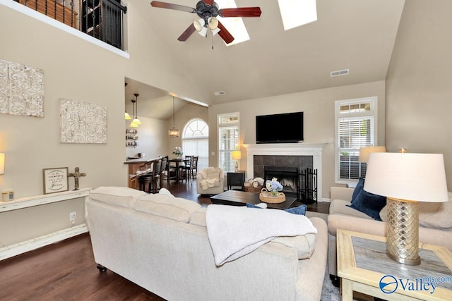 living area featuring a fireplace, plenty of natural light, dark wood finished floors, and visible vents