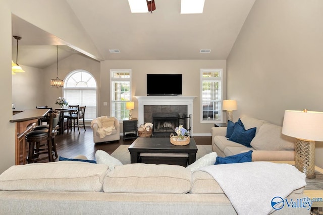 living area featuring plenty of natural light, a fireplace, vaulted ceiling, and wood finished floors