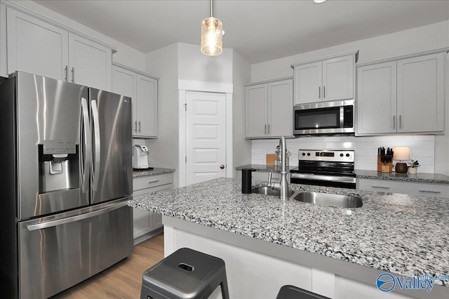 kitchen featuring tasteful backsplash, light wood finished floors, stainless steel appliances, and light stone counters