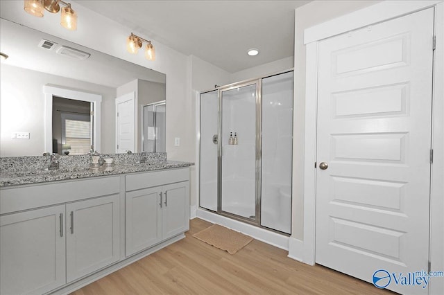 bathroom featuring vanity, a shower stall, wood finished floors, and visible vents