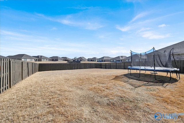 view of yard with a fenced backyard, a residential view, and a trampoline