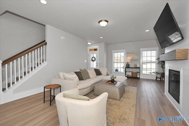 living room with a glass covered fireplace, recessed lighting, stairs, and wood finished floors