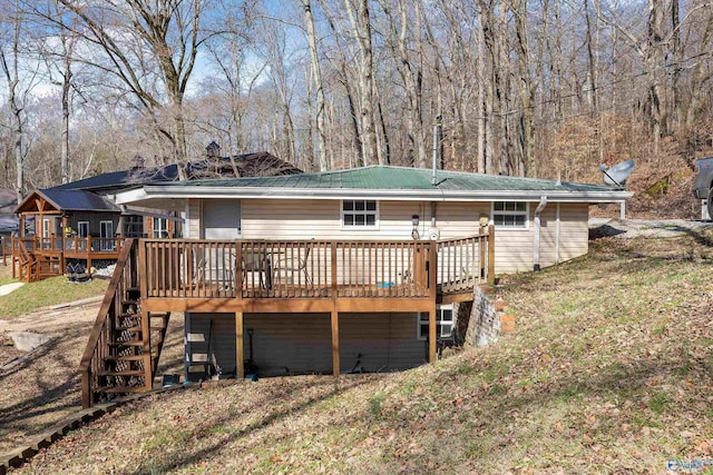 rear view of property featuring a wooden deck and a lawn