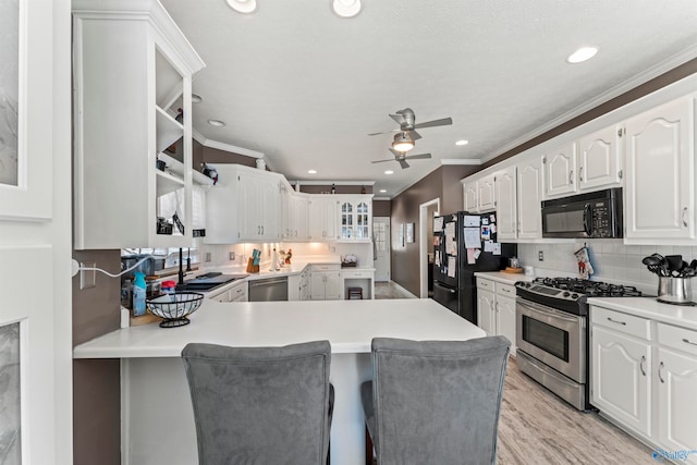 kitchen featuring black appliances, kitchen peninsula, white cabinetry, ceiling fan, and crown molding