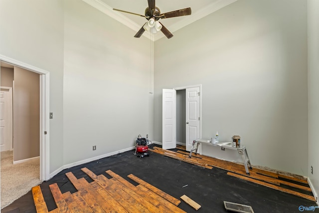 exercise room with crown molding, carpet flooring, a towering ceiling, and ceiling fan