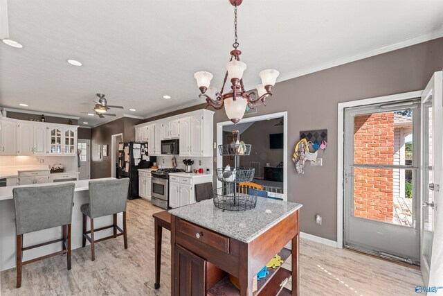 kitchen with white cabinetry, black appliances, ceiling fan with notable chandelier, light hardwood / wood-style floors, and decorative light fixtures