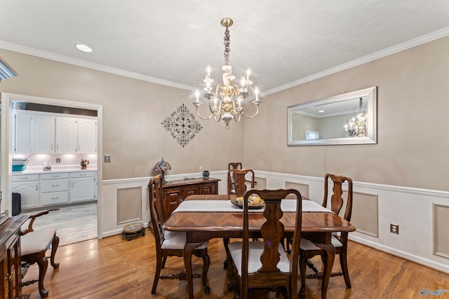 dining area featuring light hardwood / wood-style flooring, ornamental molding, and a notable chandelier