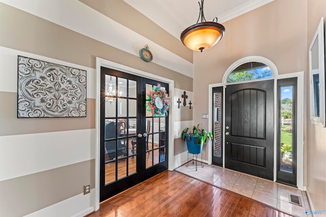 foyer with french doors, crown molding, wood-type flooring, and a healthy amount of sunlight