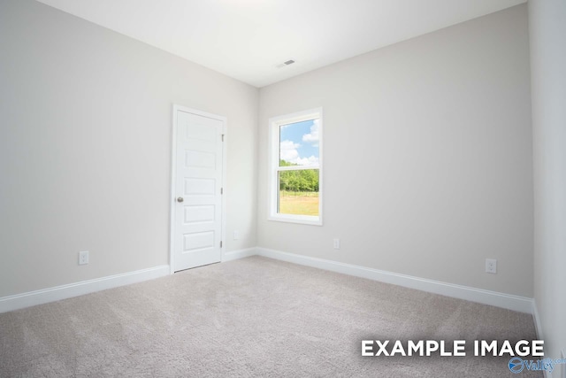 carpeted spare room with visible vents and baseboards