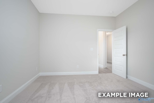 spare room with baseboards and carpet flooring