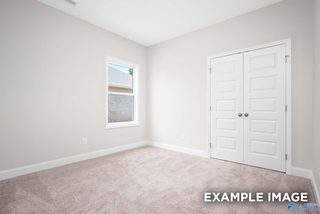 unfurnished bedroom with carpet floors, a closet, and baseboards