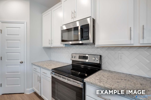 kitchen with light wood finished floors, stainless steel appliances, backsplash, white cabinetry, and light stone countertops