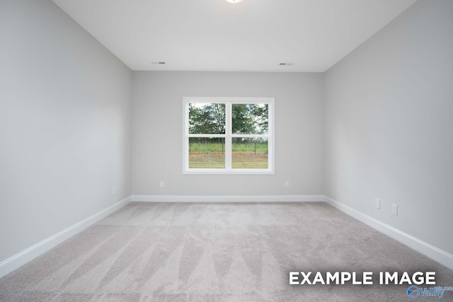 spare room featuring carpet floors and baseboards