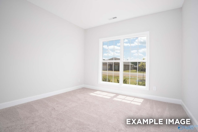 spare room featuring carpet floors, visible vents, and baseboards