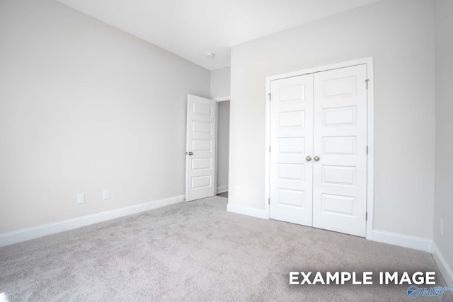 unfurnished bedroom with carpet, baseboards, and a closet