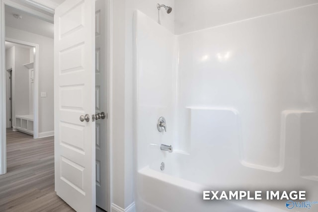 bathroom with  shower combination, wood finished floors, and baseboards