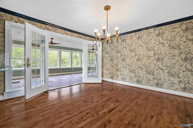 empty room featuring dark wood-type flooring, ceiling fan with notable chandelier, and crown molding