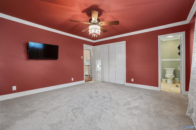 unfurnished bedroom featuring ensuite bath, a closet, carpet floors, ceiling fan, and ornamental molding