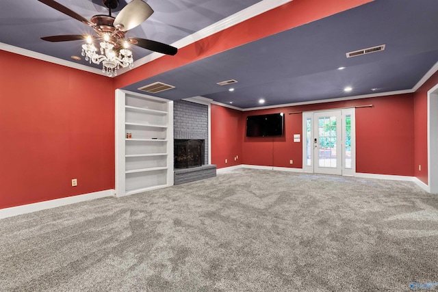 carpeted empty room with built in shelves, crown molding, ceiling fan, and a fireplace