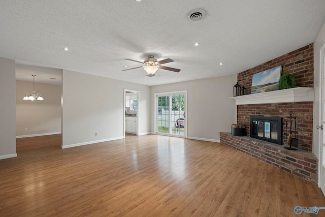 702 Royce Cir SE, Huntsville, AL 35803 - unfurnished living room featuring light wood-type flooring, ceiling fan, a fireplace, a textured ceiling, and a chandelier
