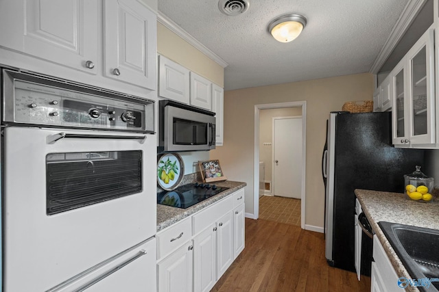 702 Royce Cir SE, Huntsville, AL 35803 - kitchen featuring stainless steel microwave, white oven, black electric cooktop, glass insert cabinets, and white cabinets