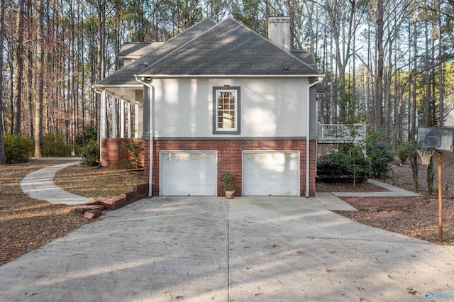 view of side of property featuring brick siding, a chimney, stucco siding, a garage, and driveway