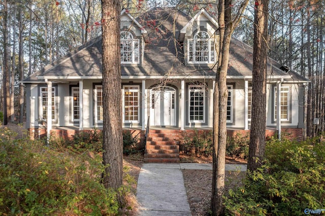 view of front of house featuring brick siding, roof with shingles, and stucco siding