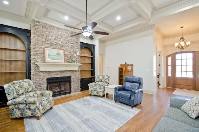 living area with wood finished floors, coffered ceiling, beam ceiling, a fireplace, and crown molding