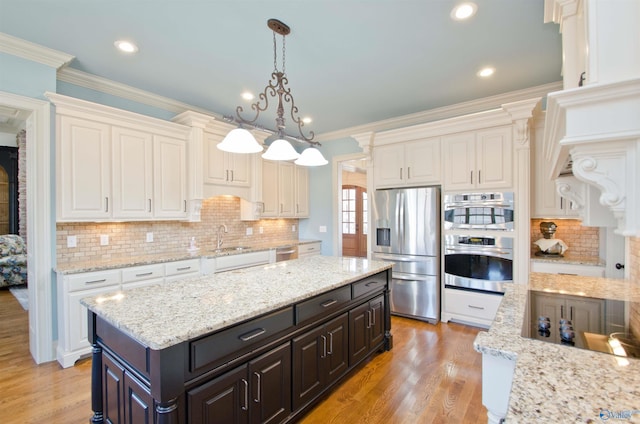 kitchen with a sink, crown molding, white cabinets, and stainless steel appliances