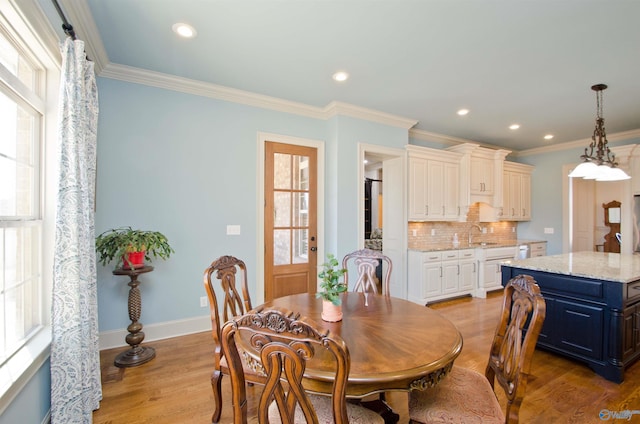 dining area with crown molding, light wood-type flooring, and baseboards