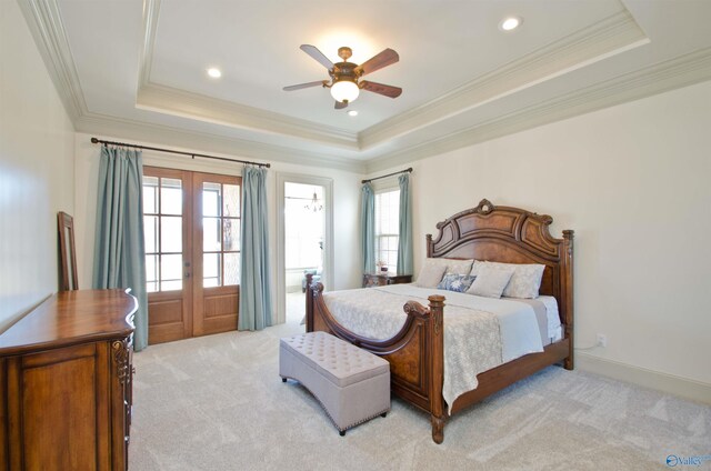 bedroom featuring a tray ceiling, light colored carpet, french doors, and ornamental molding