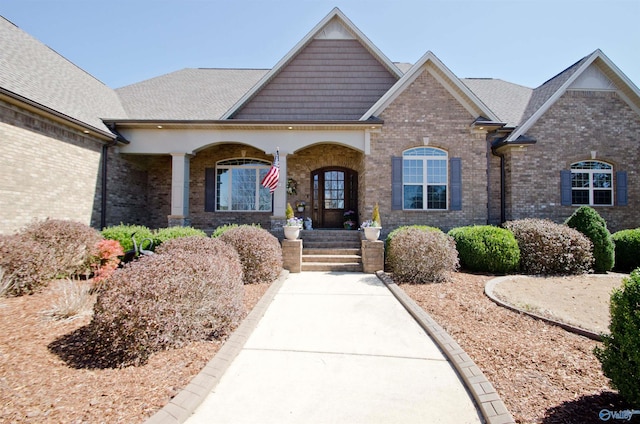 craftsman house with brick siding, a porch, and a shingled roof