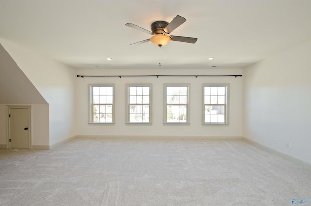 empty room featuring a wealth of natural light, light carpet, and baseboards