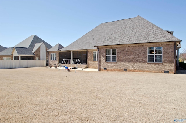 rear view of house with crawl space, brick siding, roof with shingles, and fence